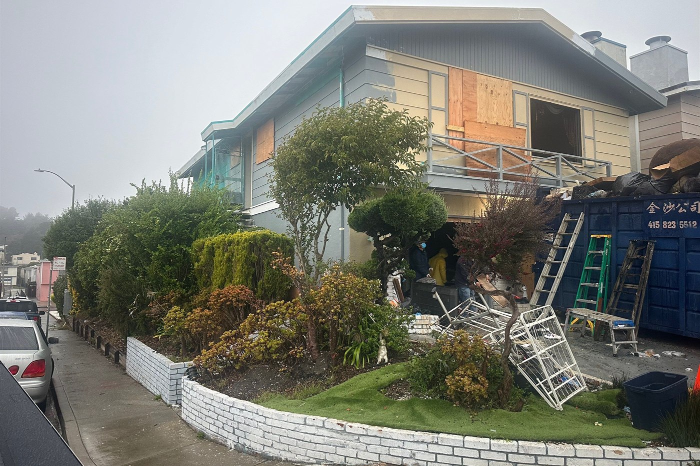 The same home before renovation, with boarded windows and construction debris
